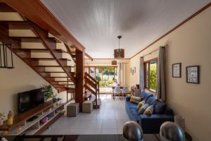 uma sala de estar com um sofá azul e uma televisão em 4 Quartos a 500m Centro - Sauna, Piscina, Fogão a Lenha, Churrasqueira - ACESSO PRIVATIVO AO AO RIO - Ideal para famílias em Nova Friburgo