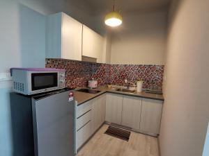 a small kitchen with a microwave and a refrigerator at Jesselton Quay Citypads in Kota Kinabalu