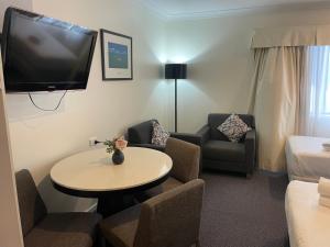 a hotel room with a tv and a table and chairs at Lakeview Motor Inn in Belmont