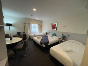 ein Hotelzimmer mit 2 Betten und einem Tisch in der Unterkunft Lakeview Motor Inn in Belmont