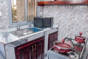 a kitchen with a stove and a sink and a microwave at Home Away From Home in Yaoundé