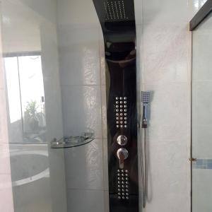 a bathroom with a shower with a wooden clock on the wall at Lili's Hostel in Santa Cruz de la Sierra