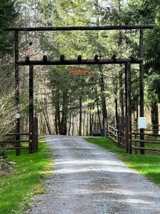 uma estrada de terra através de um arco de madeira com uma cerca em The Loft At The Nisqually Highland Ranch em Eatonville