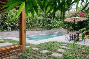 a swimming pool with a table and an umbrella at Piripe Wellness Lodge in Pacto