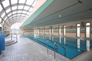 a swimming pool in a building with a glass ceiling at Rembrandt Hotel Oita in Oita