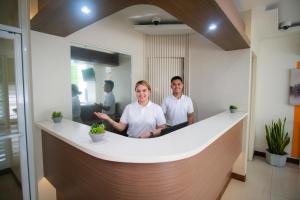 Um homem e uma mulher num balcão num escritório. em Benrose Hotel em Cagayan de Oro