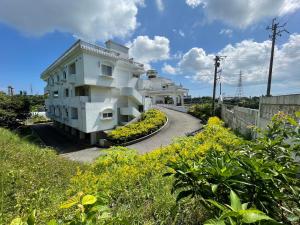 a white building with a walkway next to a field of flowers at Hotel Sha La La in Okinawa City