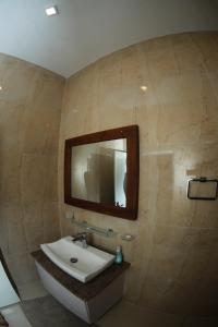 ein Bad mit einem Waschbecken und einem Wandspiegel in der Unterkunft Kosgama Riverside Resort in Kosgama