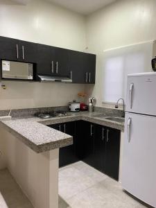 eine Küche mit schwarzen Schränken und einem weißen Kühlschrank in der Unterkunft Villa en Salinas vía Punta Carnero in Salinas