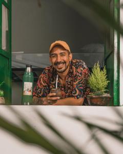 un hombre está sonriendo mientras toma un trago en Wild Monkey Hostel, en Cuenca