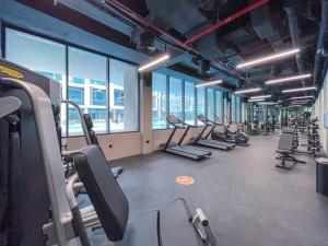a gym with rows of tread machines and windows at Modern flat with KING SIZE bed and HIGH SPEED Wifi in Dubai