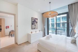 a white bedroom with a large bed and a dining room at Modern flat with KING SIZE bed and HIGH SPEED Wifi in Dubai