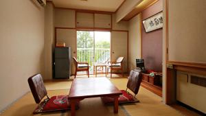 a room with a table and chairs and a kitchen at Takasago Onsen in Asahikawa