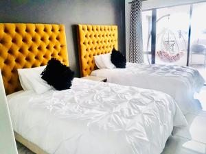 two beds with white sheets and a yellow headboard at Luxury on 1B Patricia in Ballito