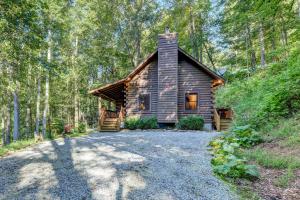 une cabane en rondins au milieu d'une forêt dans l'établissement Waynesville Cabin with Covered Deck and Fire Pit!, à Lake Junaluska