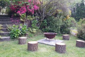 a grill sitting between three tree stumps in a garden at Paradise Valley River Lodge in Rotorua