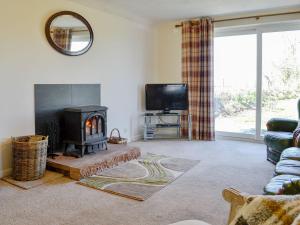 a living room with a fireplace and a tv at Angerton Cottage in Kirklinton