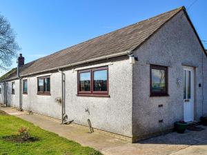 a white brick house with windows on a street at Angerton Cottage in Kirklinton