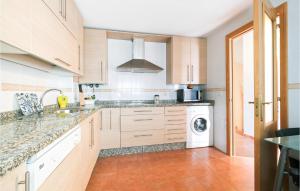 a kitchen with wooden cabinets and a washer and dryer at Stunning Home In La Algaba With 3 Bedrooms in La Algaba