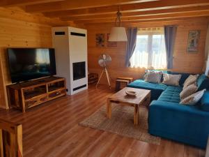 a living room with a blue couch and a television at Panorama Tatry Chalets in Veľká Lomnica