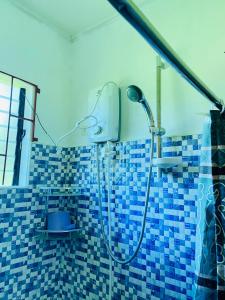 y baño con ducha y azulejos azules. en Uptown Guesthouse en Siquijor