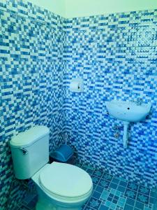Baño de azulejos azules con aseo y lavamanos en Uptown Guesthouse en Siquijor