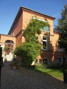 un bâtiment en briques avec un arbre devant lui dans l'établissement Ferienwohnung Markert, à Blankenburg