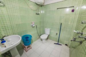 een groene betegelde badkamer met een toilet en een wastafel bij Yangsum Heritage Farm in Rinchingpong