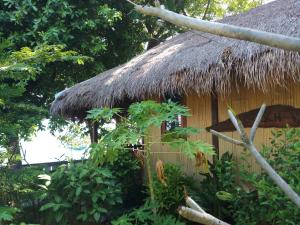 Cabaña con techo de paja y algunos árboles en Lena house Flores en Hitokalak