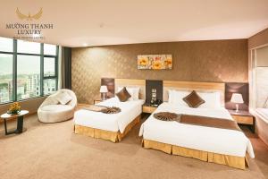 um quarto de hotel com duas camas e uma cadeira em Muong Thanh Luxury Nha Trang Hotel em Nha Trang