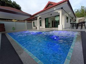 una piscina con acqua blu di fronte a una casa di Luxury Private Pool Villa with Jacuzzi and Kids Pool at Royal Park Village - Walk to the Beach a Jomtien Beach