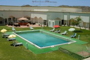 een groot zwembad met stoelen en parasols bij OYO 142 Al Sharqiya Sands Hotel in Ibrā