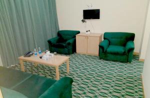 a living room with two green chairs and a table at OYO 142 Al Sharqiya Sands Hotel in Ibrā