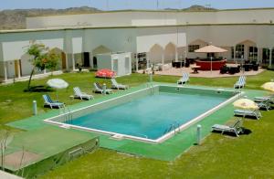 duży basen na dziedzińcu z krzesłami i parasolami w obiekcie OYO 142 Al Sharqiya Sands Hotel w mieście Ibrā