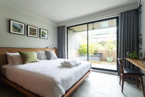 a bedroom with a bed and a desk and a window at GalileOasis Boutique Hotel in Bangkok