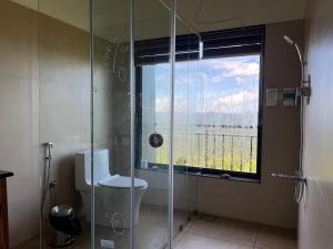 baño con ducha, aseo y ventana en Titha Service Villa, en Santhanpara