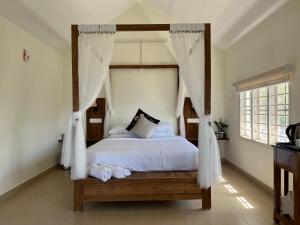 1 dormitorio con cama con dosel y ventana en Titha Service Villa, en Santhanpara
