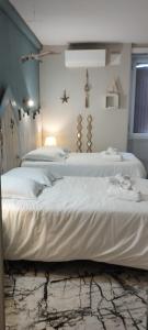 two beds in a room with white sheets and a lamp at Résidence LE11B in Uzerche