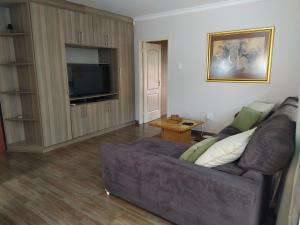 a living room with a couch and a flat screen tv at Twins Guest House Astoni in Vanderbijlpark