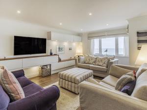 a living room with couches and a flat screen tv at Apartment 18, Burgh Island Causeway in Kingsbridge