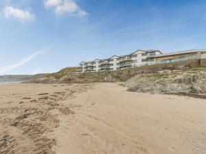 a beach with a building on a hill next to the ocean at Apartment 18, Burgh Island Causeway in Kingsbridge