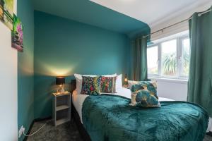 a blue bedroom with a bed and a window at J's Home Away From Home FrEsH 2 Bedroom Garden Parking in Hull