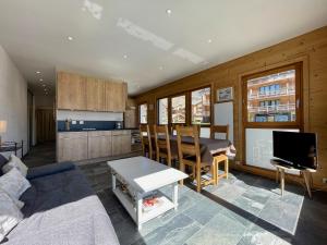 sala de estar con sofá, mesa y TV en Alpes Sweet Home - Résidence La Menandière W1 en L'Alpe-d'Huez