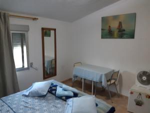 a bedroom with a table and a bed with a blue blanket at Nice room with swimming pool in Cocentaina