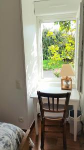 1 dormitorio con escritorio y ventana con lámpara en Aux Chambres du Chadoux de Chateaubourg (ChaChaCha), en Châteaubourg