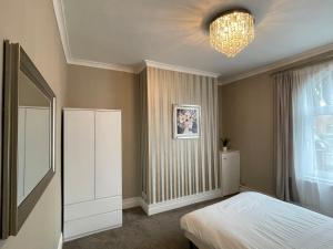 1 dormitorio con cama y lámpara de araña en Moda House Wigan - Beautiful 4 Bed Property en Pemberton