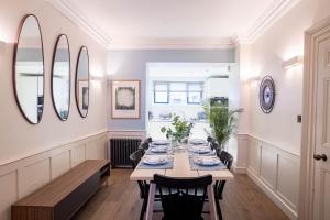 een eetkamer met een tafel, stoelen en spiegels bij Liverpool St Three Bedroom Home near Tube Station in Londen