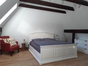 a bedroom with a white bed and a red chair at Schönes Apartment vor den Toren Hamburgs - keine Monteurwohnung in Asendorf