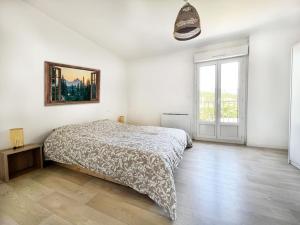 a white bedroom with a bed and a large window at Charmant T3 en plein centre du Bousquet-d'Orb in Le Bousquet-dʼOrb +12 photos