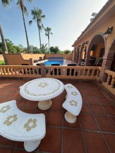 a patio with two tables and benches and a pool at Villa Mandolyn in Alhaurín de la Torre